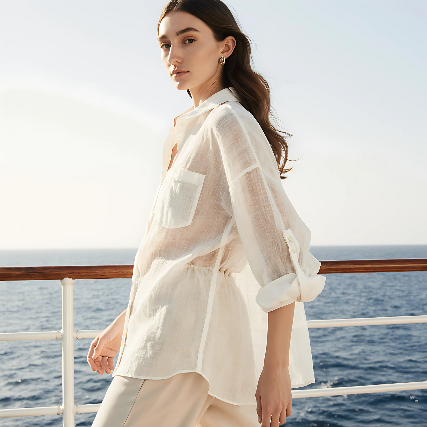 Woman wearing Aire Button-Down Shirt with soft gauze texture, standing by the ocean, showcasing resortwear style.
