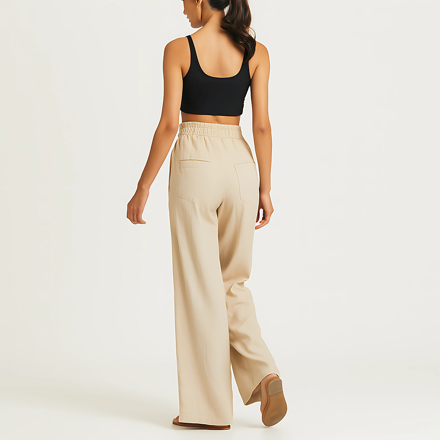 Woman wearing natural Coastal Drape Pant with elastic waistband, ideal for resortwear and wellness spas, back view.