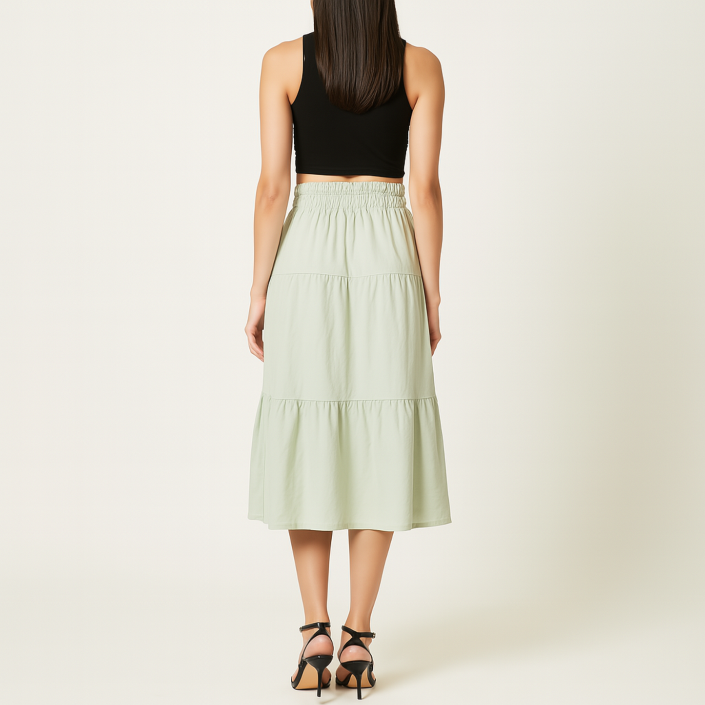 Woman wearing Luma Cotton Midi skirt in mint green, showcasing high-rise elastic waistband and tiered design for a breezy look.