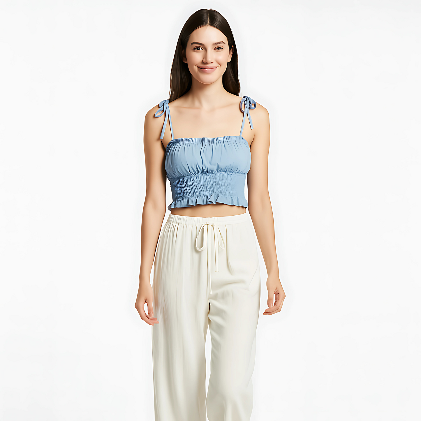 Sky blue ruched cami with bow-tied straps and ruffle hem, perfect for summer and resort wear, paired with cream-colored trousers.