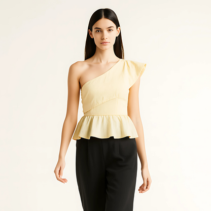 Woman wearing an asymmetric ruffle top with one shoulder design and peplum hem, ideal for eventwear and resort collections.
