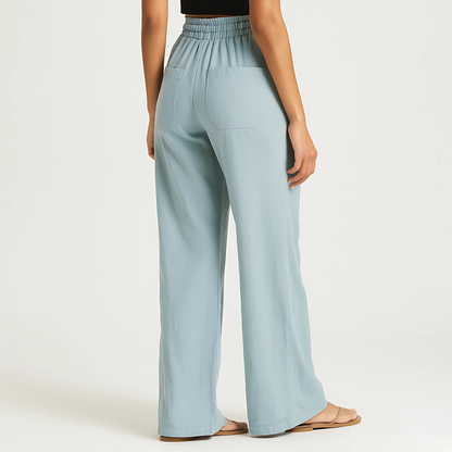 Woman wearing powder blue Coastal Drape Pant with elastic waistband, relaxed wide-leg style, ideal for resortwear and warm weather.
