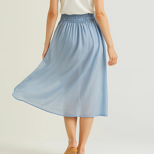 Woman wearing Isla Elastic Midi Skirt in Cloud Blue, featuring a wide elastic waistband and flowing fabric for resort and travel wear.