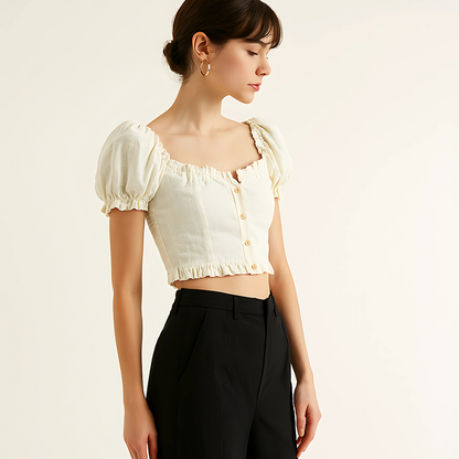 Woman wearing a natural linen button crop top with puff sleeves and ruffle trim, styled for resortwear or feminine collections.