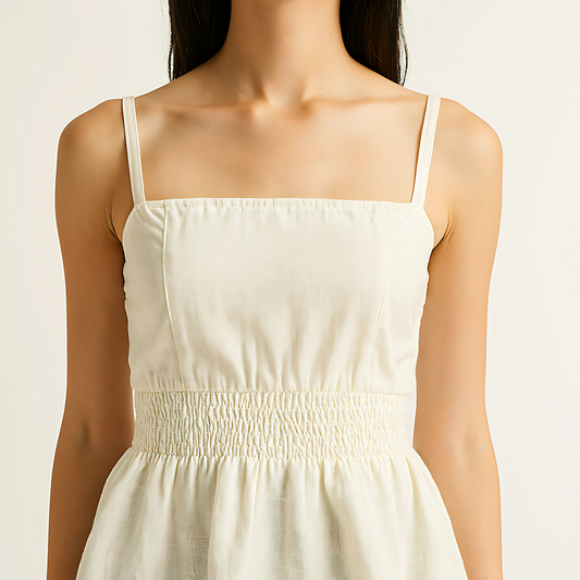 Ivory shirred peplum cami with square neckline and adjustable straps, featuring a structured bodice and flared waist.