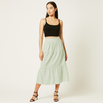 Model wearing mint green Luma Cotton Midi skirt with elastic waistband and tiered design, paired with black top and sandals.