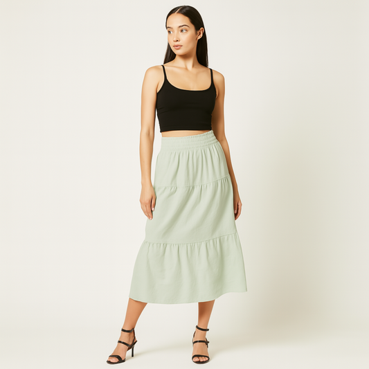 Model wearing mint green Luma Cotton Midi skirt with elastic waistband and tiered design, paired with black top and sandals.