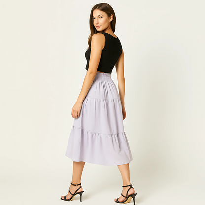 Woman wearing Luma Cotton Midi skirt in soft lilac. Tiered design, high-rise waistband. Ideal for resortwear, spa retail, and spring fashion.