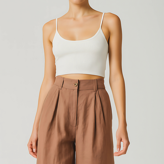 Woman wearing high-waisted terracotta Solana Linen Trousers with a white crop top, displaying wide-leg design and front pleats.